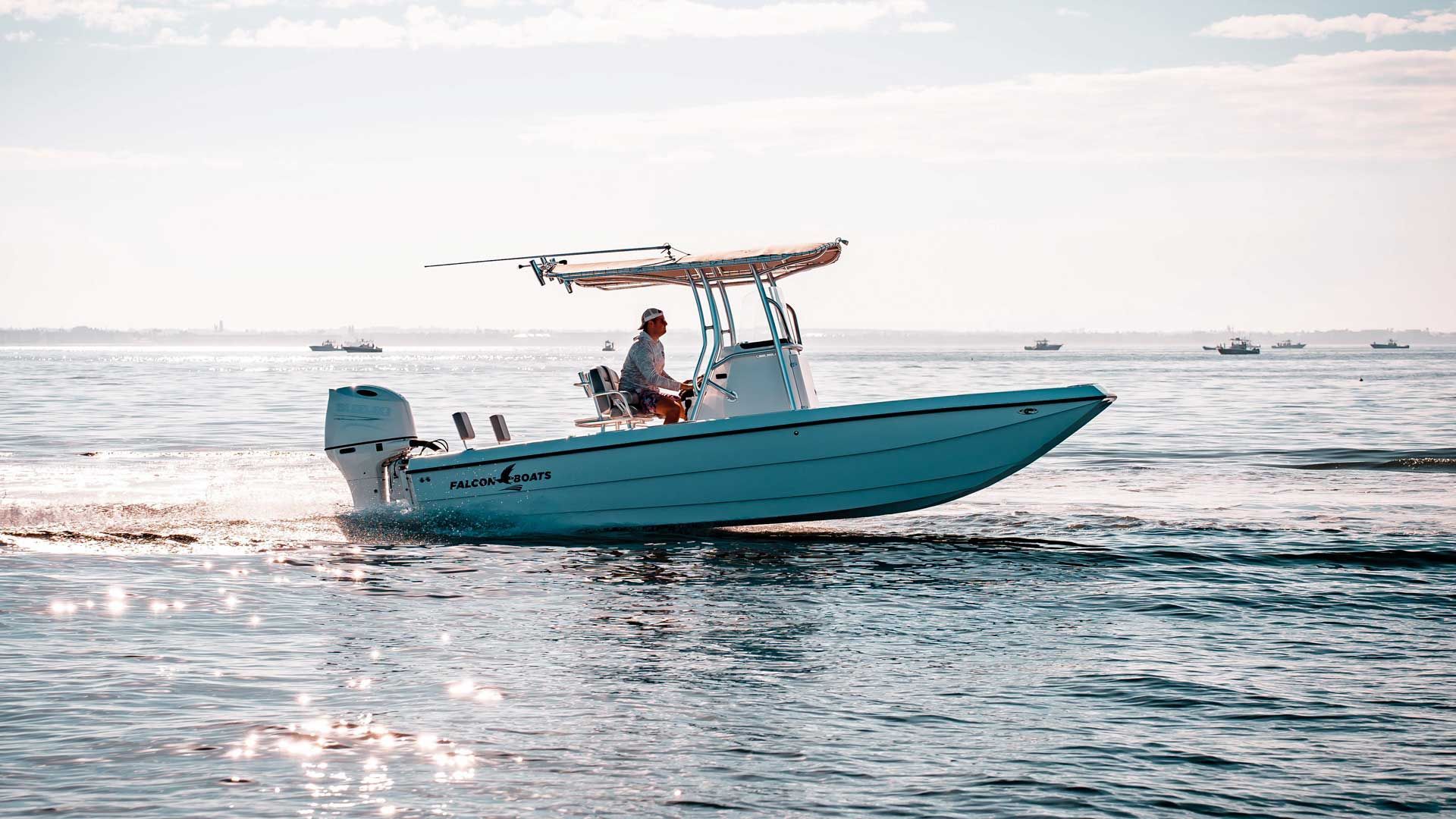 A light blue motorboat on the water with a person at the helm, under a bright sky.
