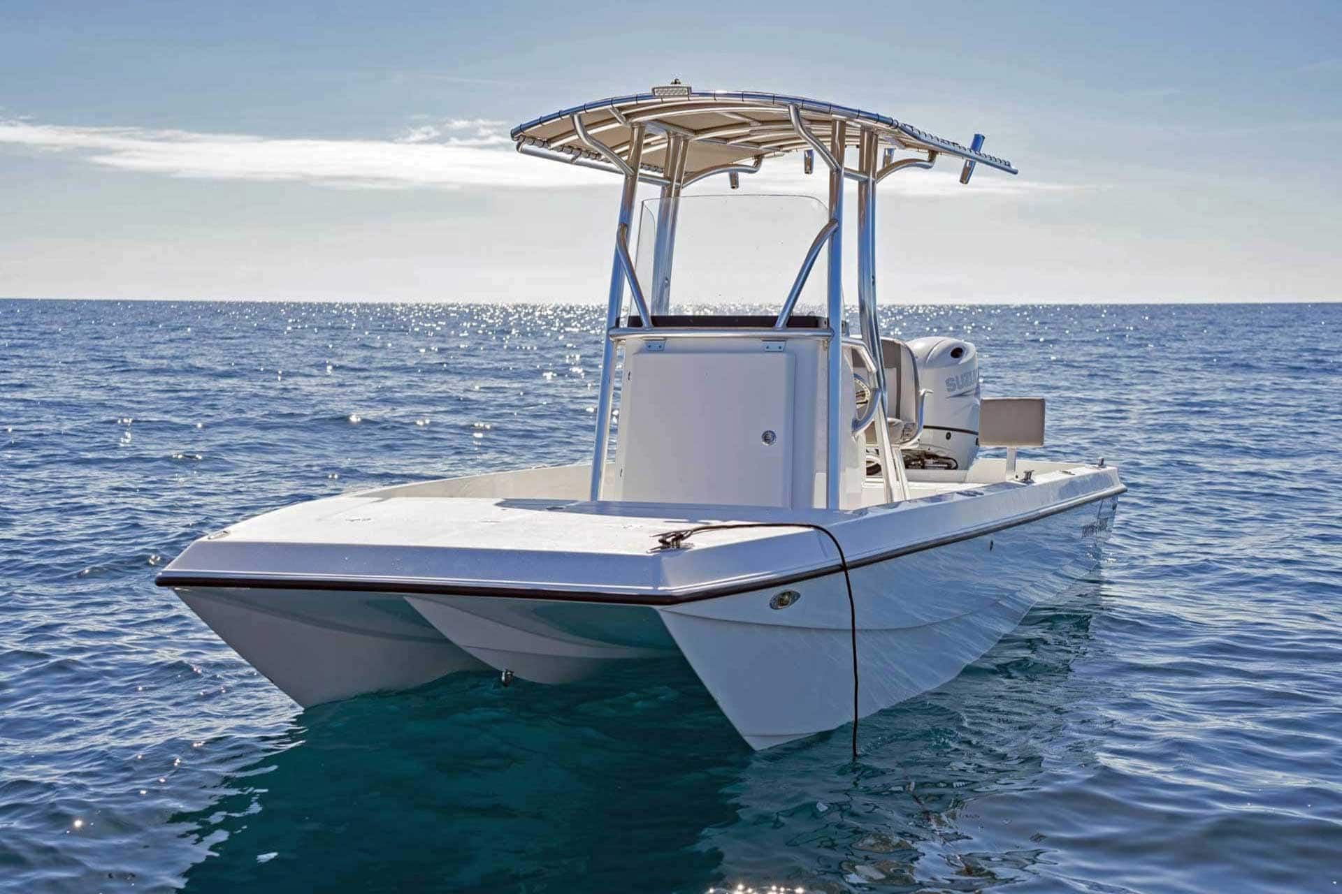 White catamaran boat on calm blue water with a sunny sky.