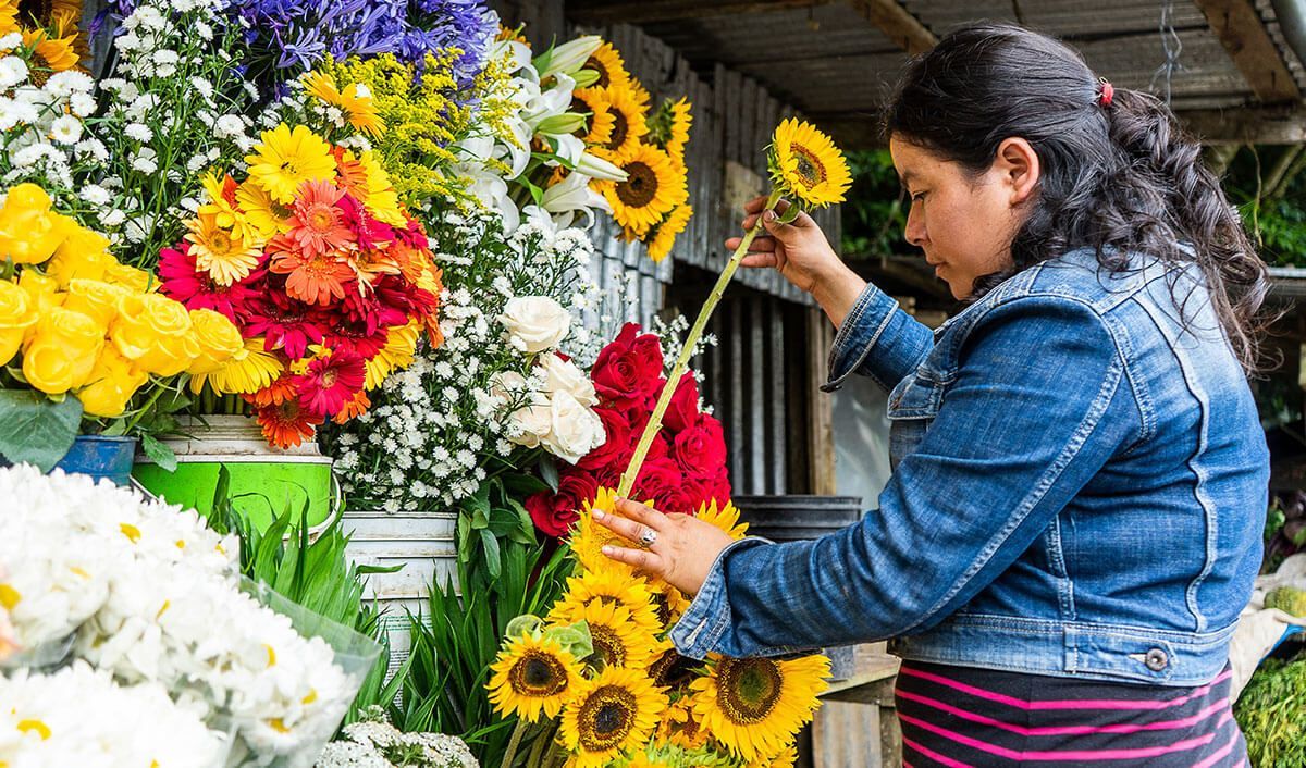 Woman adding sunflowers to a colorful display of flowers for a Catholic funeral