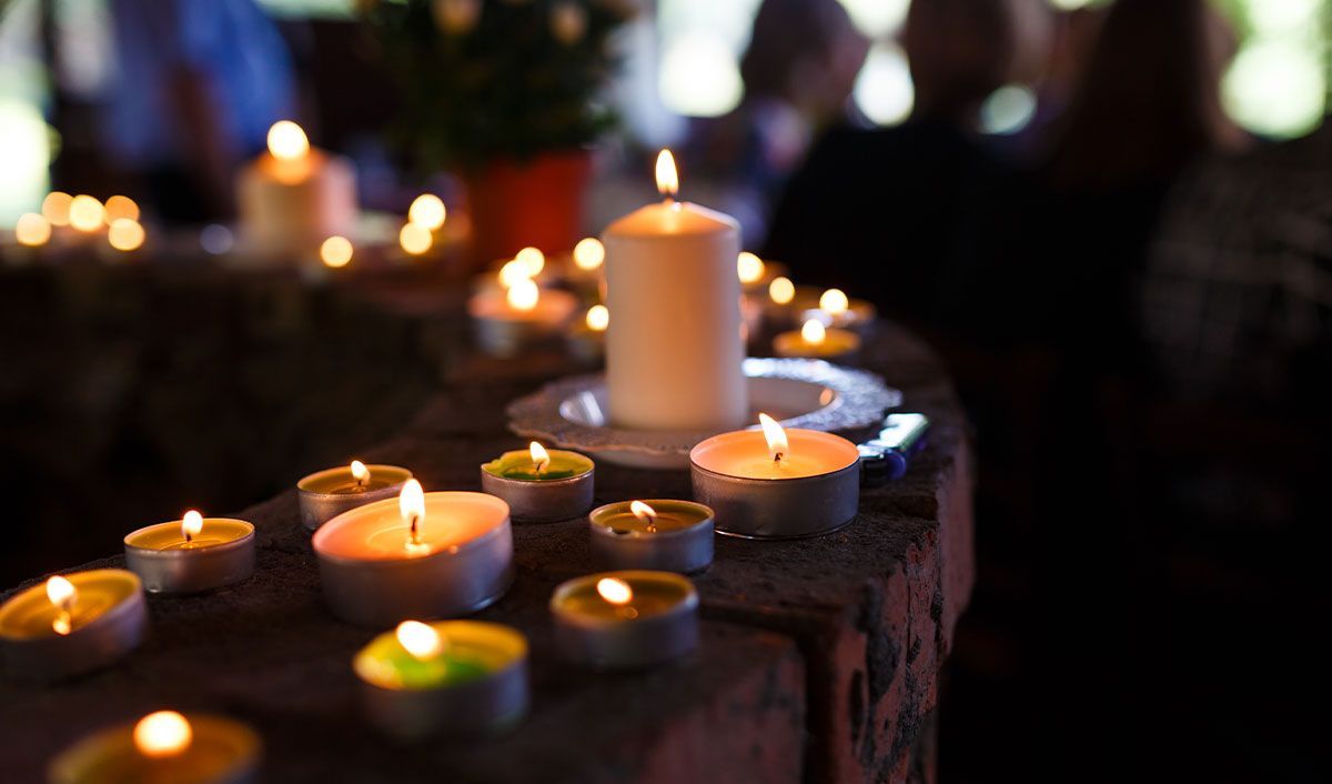 A ring of candles in varying sizes lit for an outdoor memorial service.