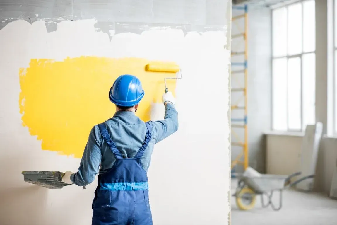 Professional painter applying yellow paint to an interior wall.