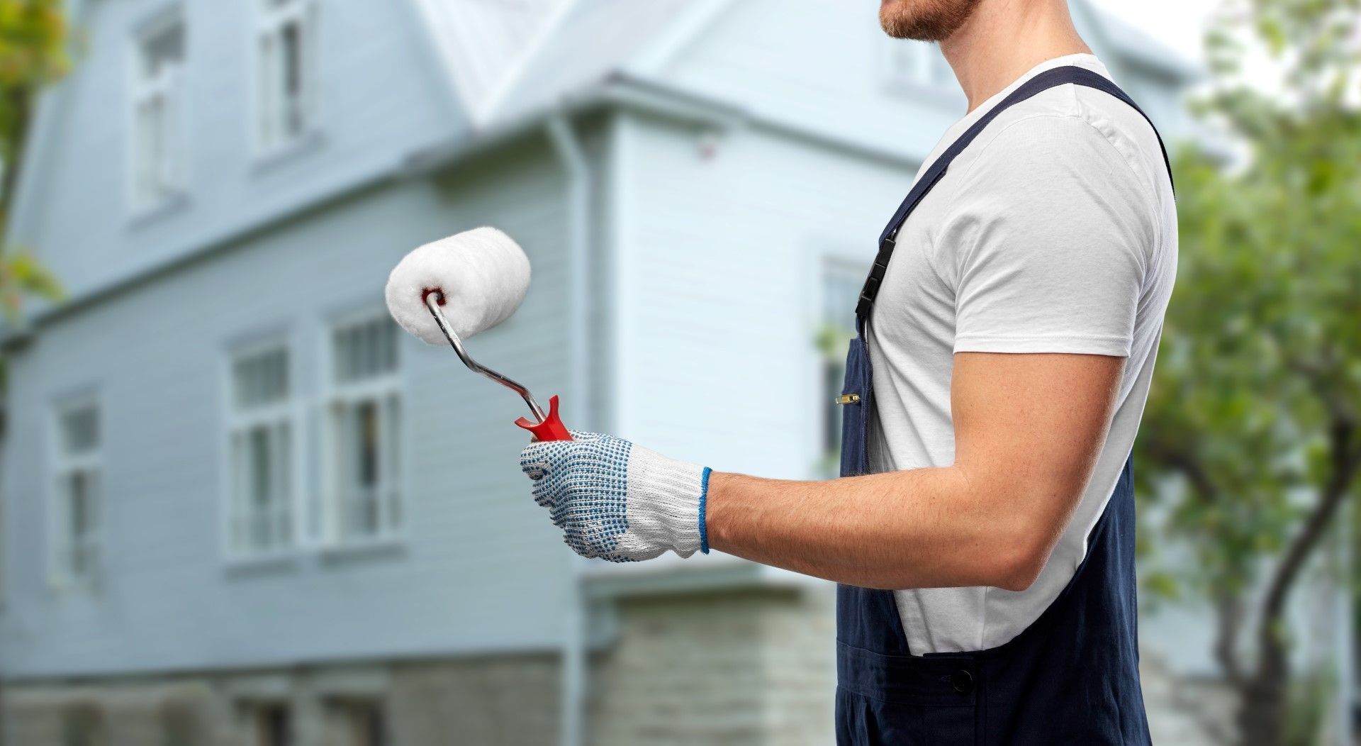 Professional exterior painter holding a paint roller outdoors.