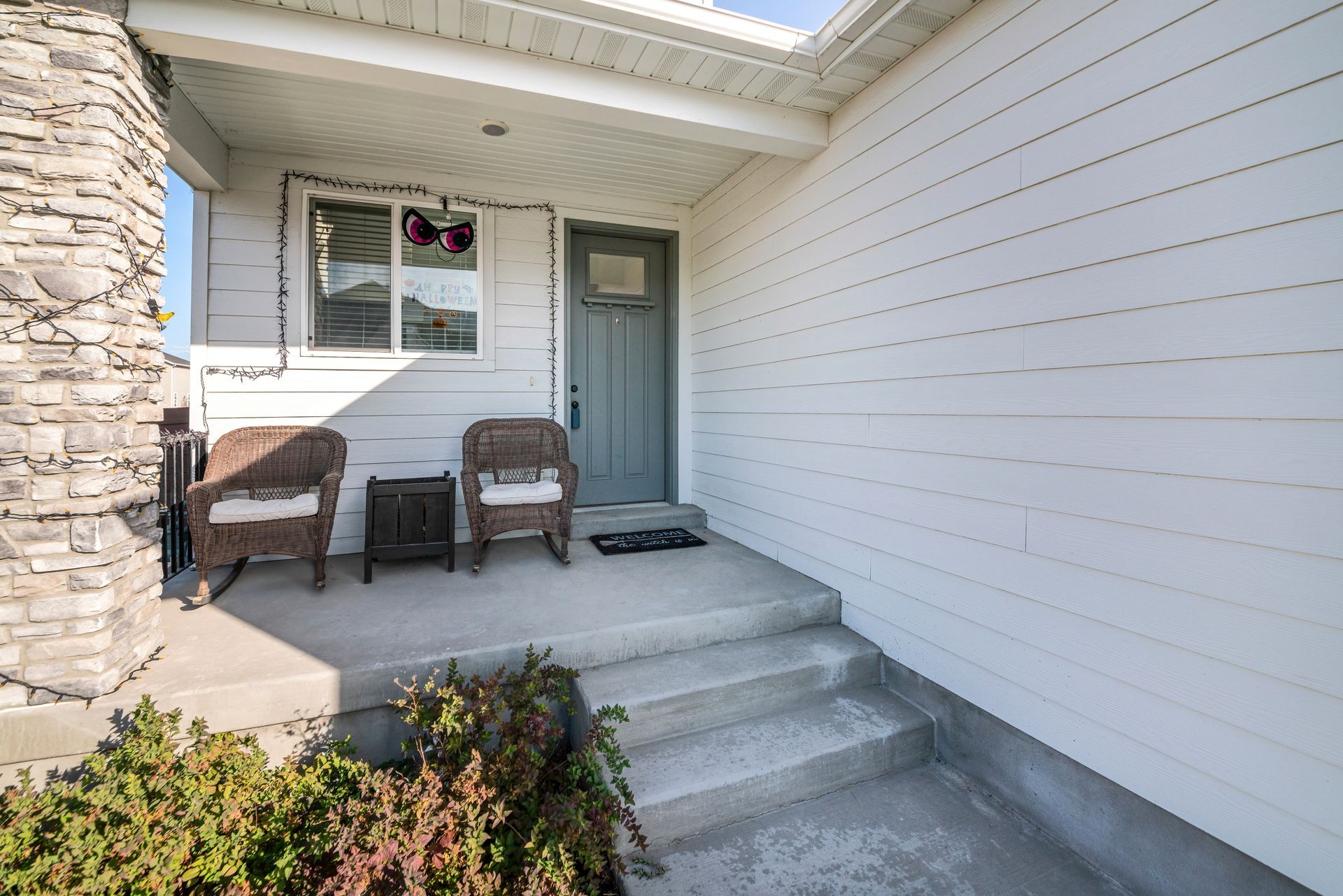 A porch with chairs and a table in front of a house.