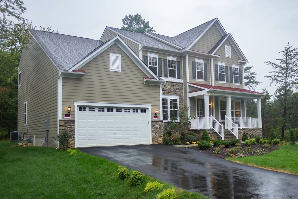 A large house with a white garage door is on a rainy day.