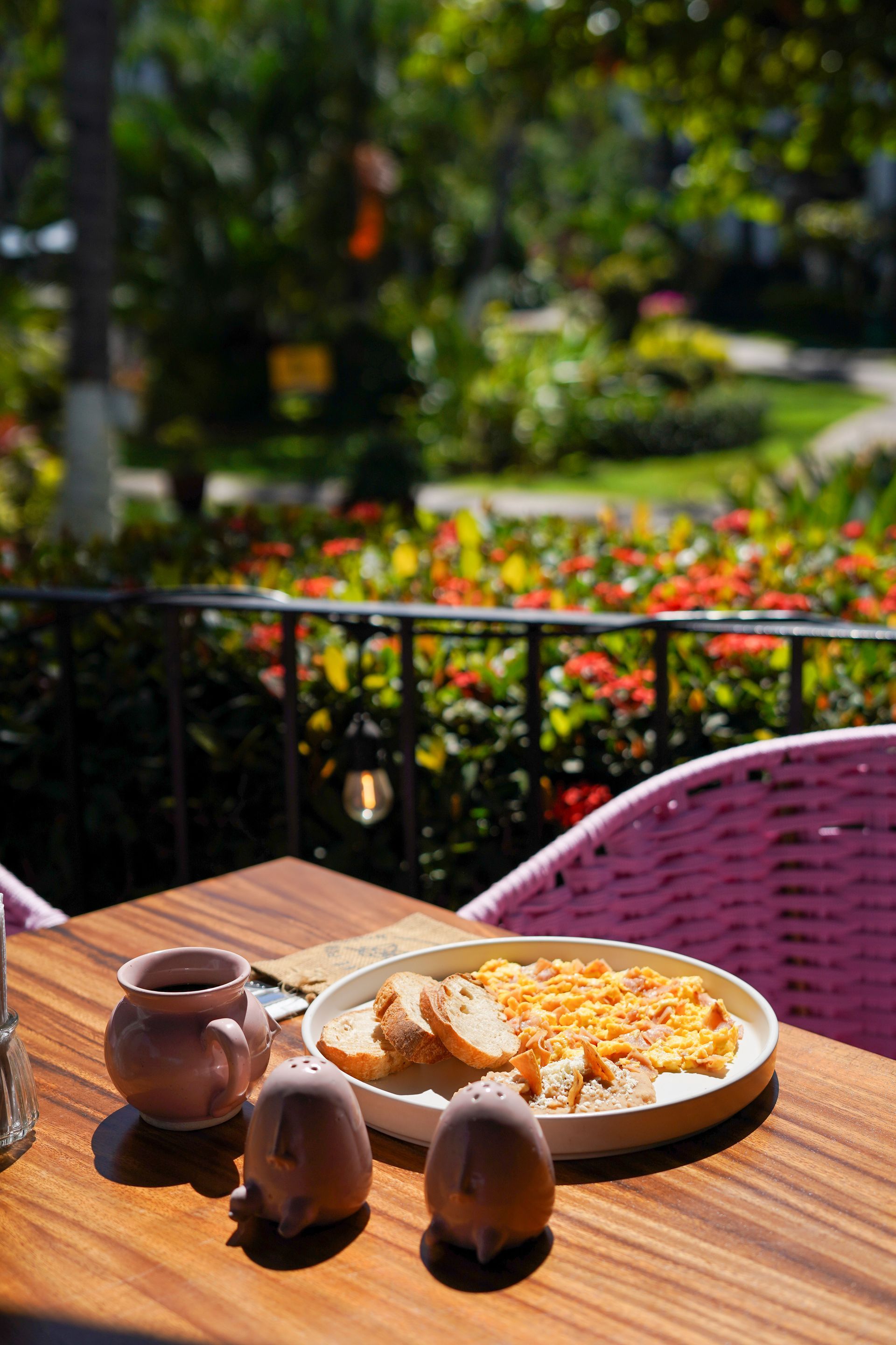 Breakfast plate with toast on a wooden table, outdoor setting, blurry garden view.