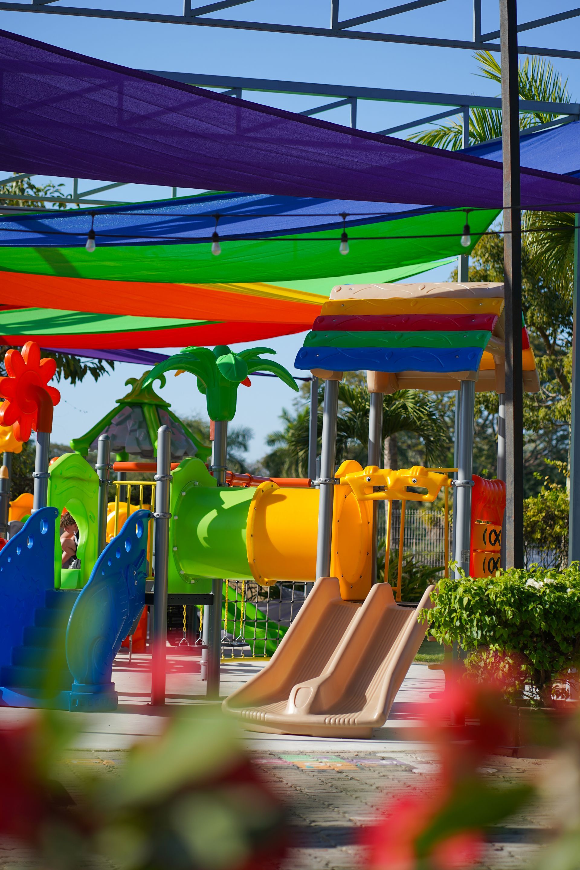 Brightly colored playground with slides and overhead rainbow canopy.