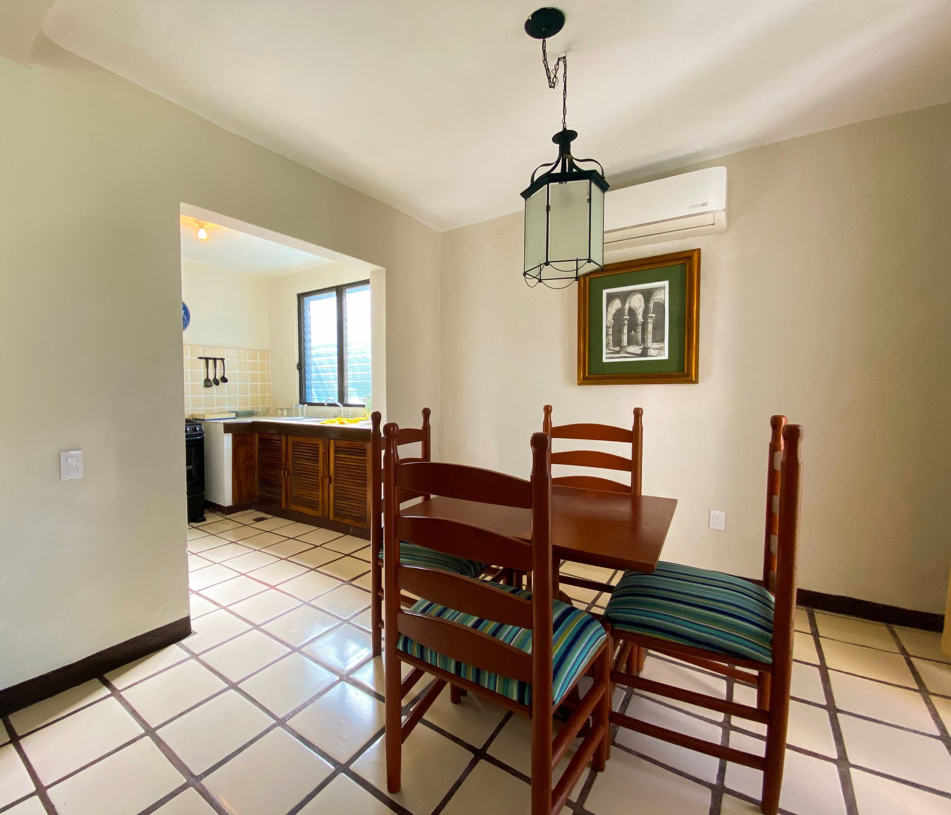 Dining area with a table and chairs, adjacent to a kitchen with wooden cabinetry.