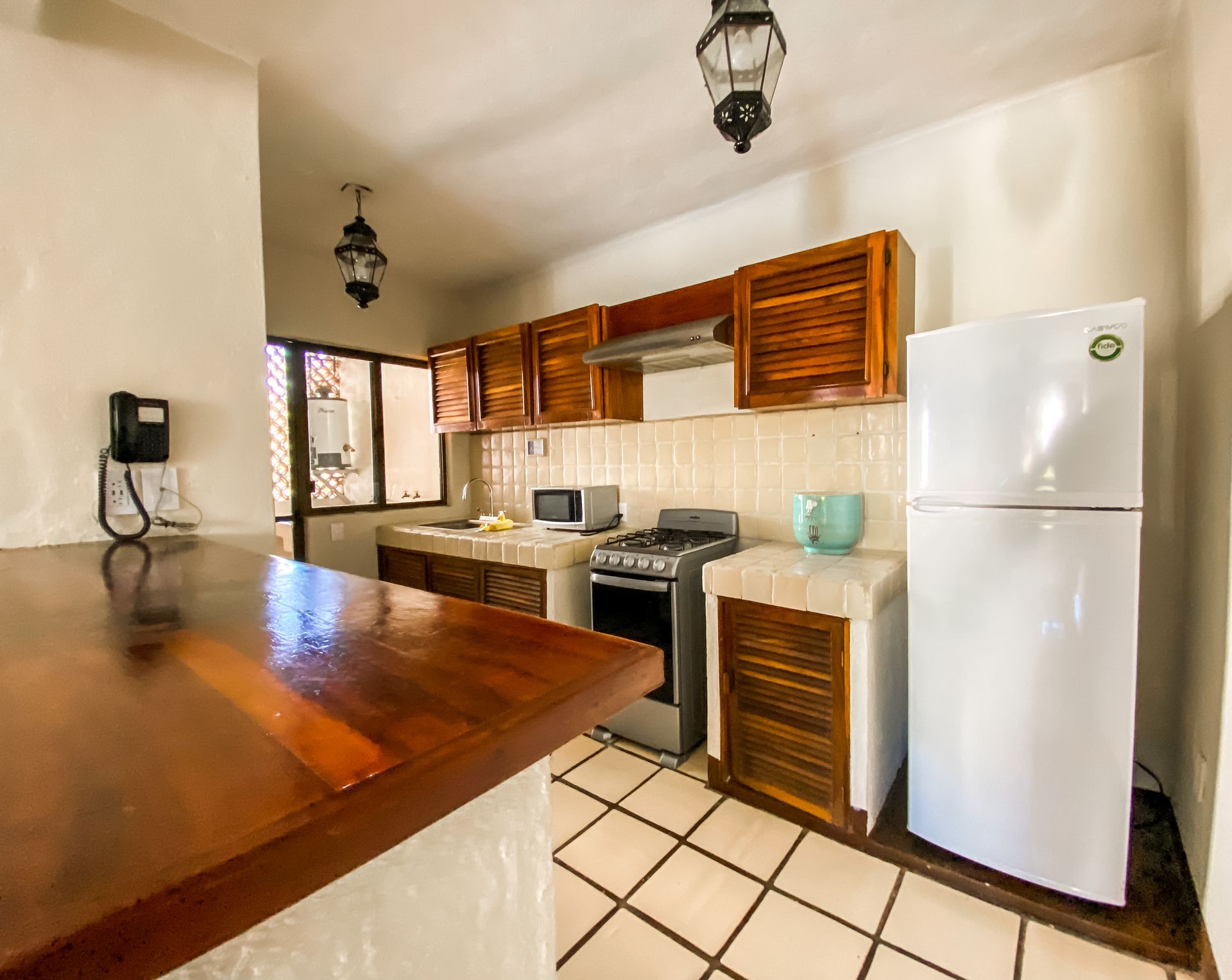 Kitchen with wood cabinets, white appliances, and a bar.
