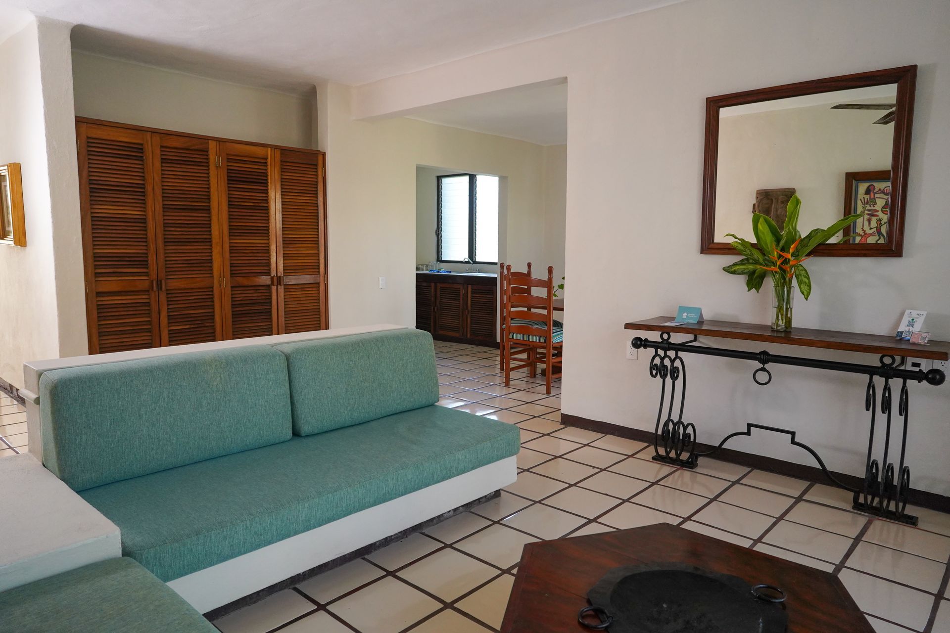 Living room with turquoise couch, wooden furniture, and tile floor.