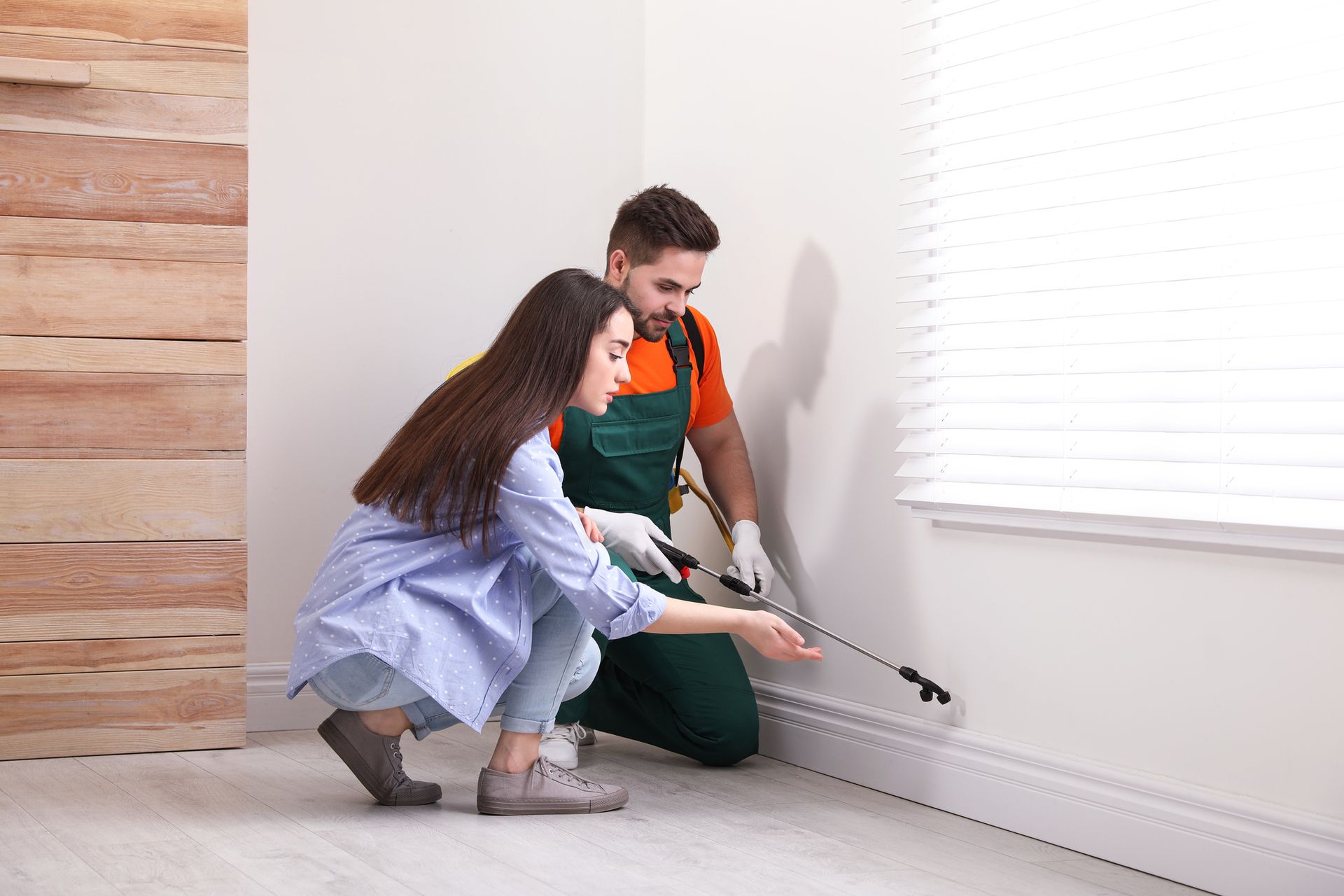 An exterminator is performing residential pest control services with a female client. — Port St. Lucie, FL — Goodfella's Pest Management Inc