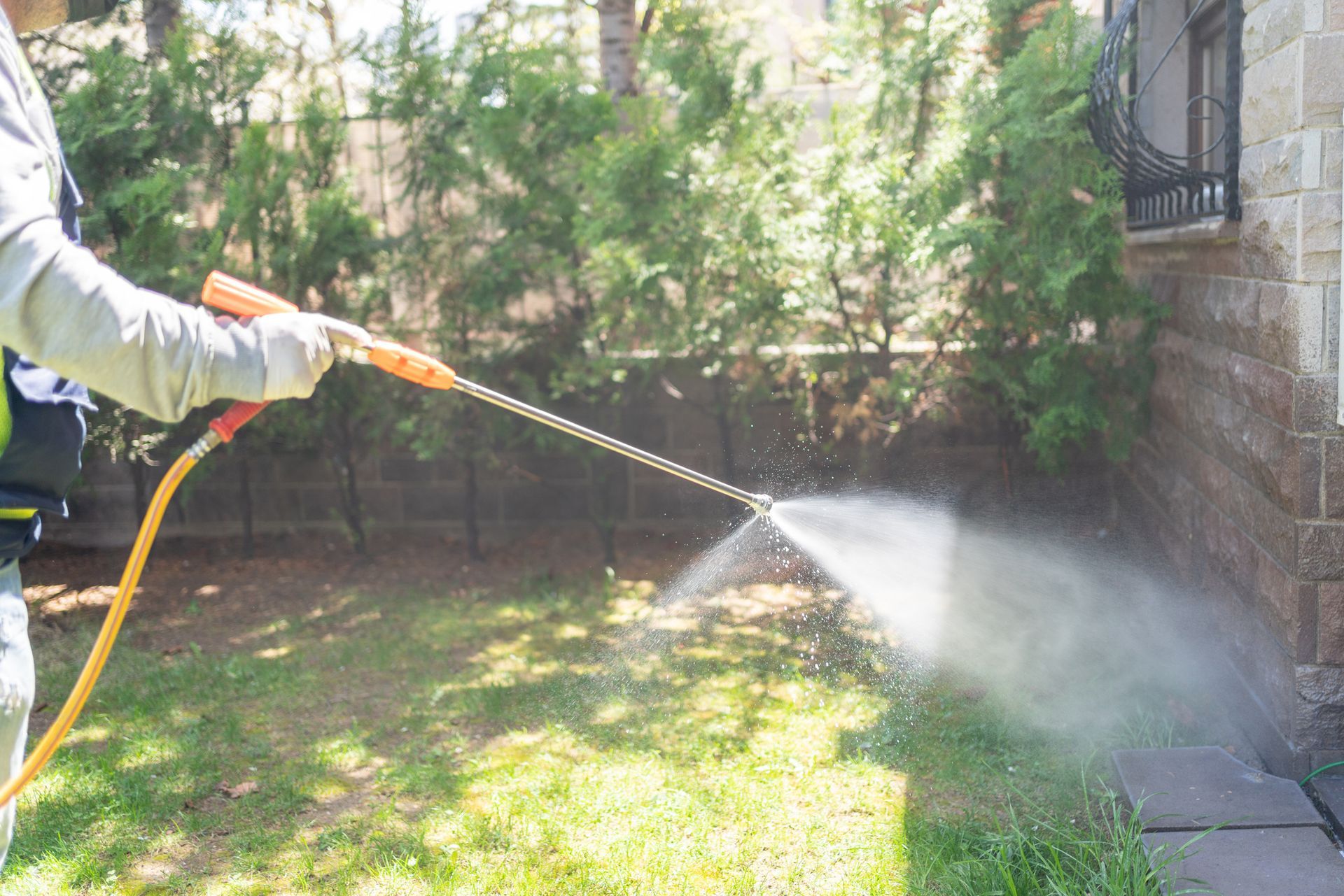 An exterminator is performing residential pest control services outdoors. — Port St. Lucie, FL — Goodfella's Pest Management Inc