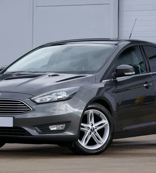 A black ford focus is parked in front of a building.