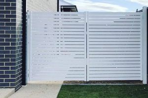 A white fence is sitting in front of a brick building.