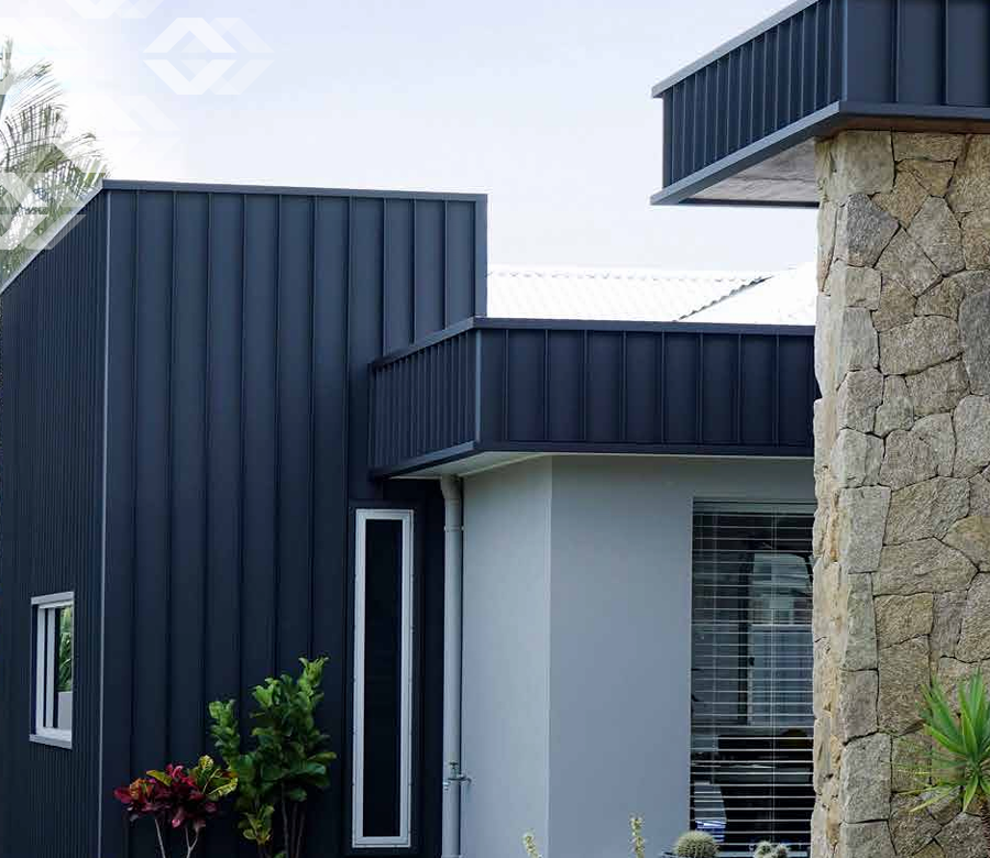 A black and white house with a stone wall and a black roof.