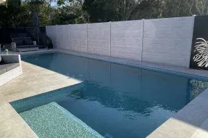 A large swimming pool with a white fence surrounding it.