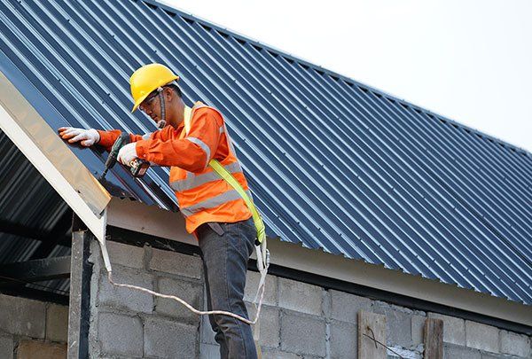 Worker Using Hand Drill To Install Metal Sheet Onto Roof — Metal Roofing in Coffs Harbour, NSW