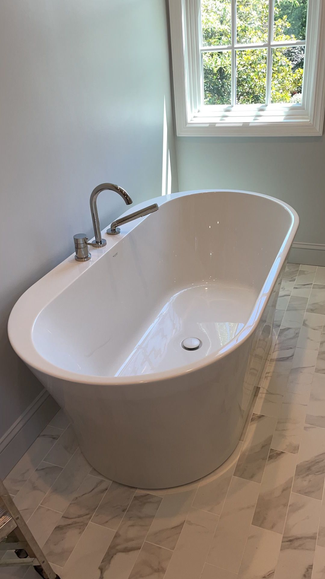 A white bathtub is sitting in a bathroom next to a window.