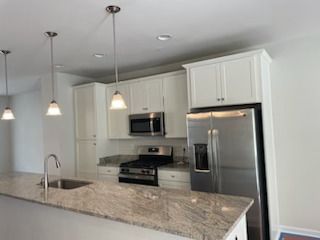 A kitchen with white cabinets, stainless steel appliances, granite counter tops, and a refrigerator.