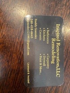 A business card for inspired renovation llc is on a wooden table.