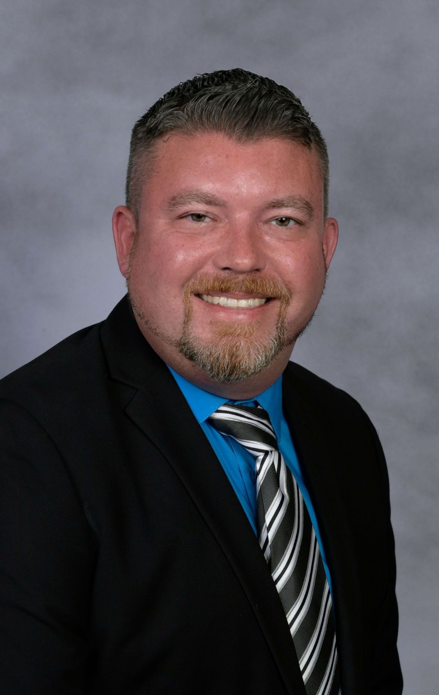 A woman in a blue jacket is smiling for the camera.