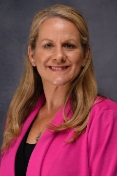 A woman in a blue jacket is smiling for the camera.