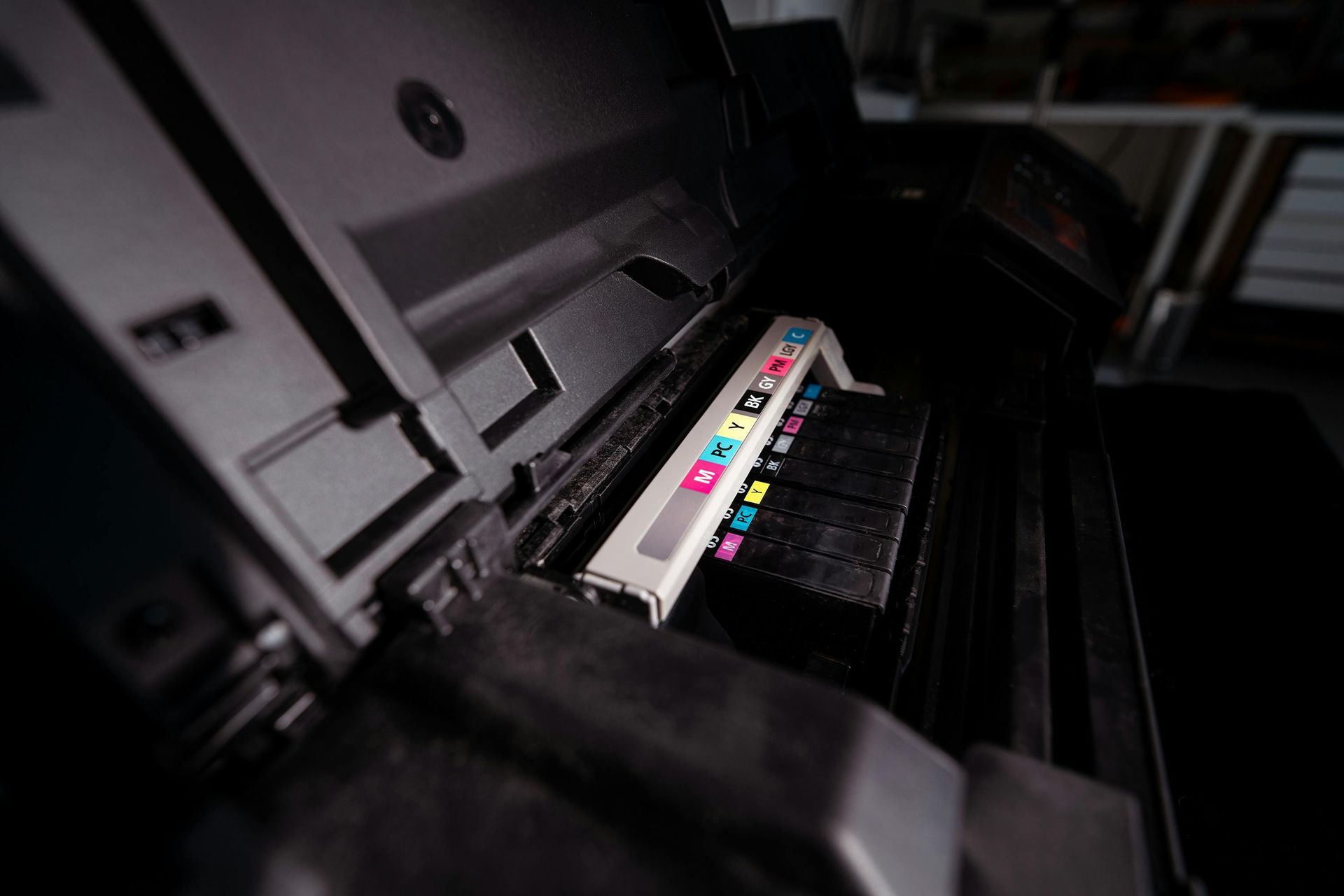Printer ink cartridge bay with colorful ink labels inside a machine