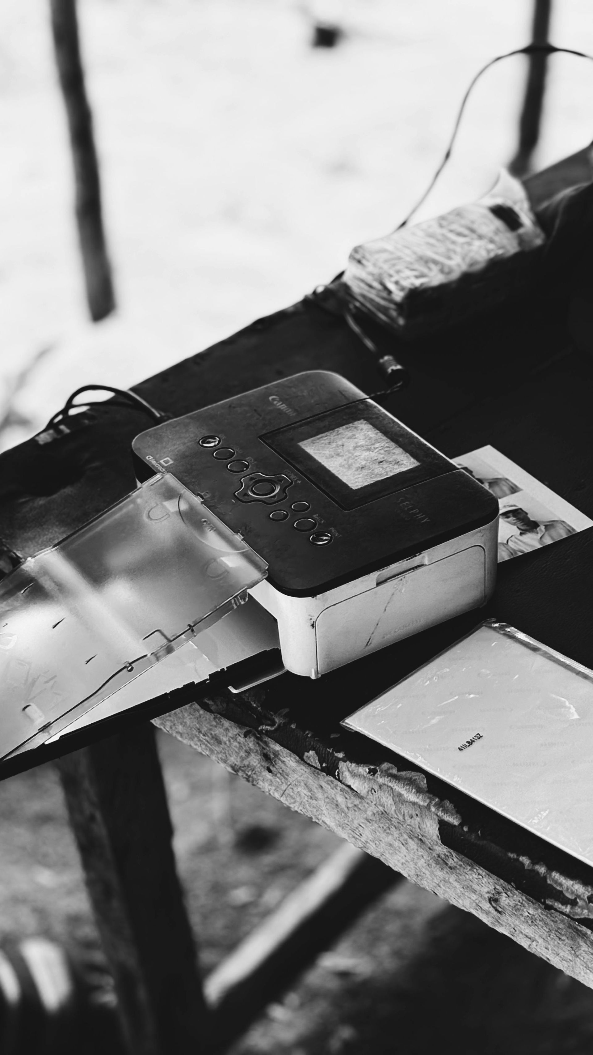Small black-and-white device with a cord lying on a worn wooden table near scattered papers.
