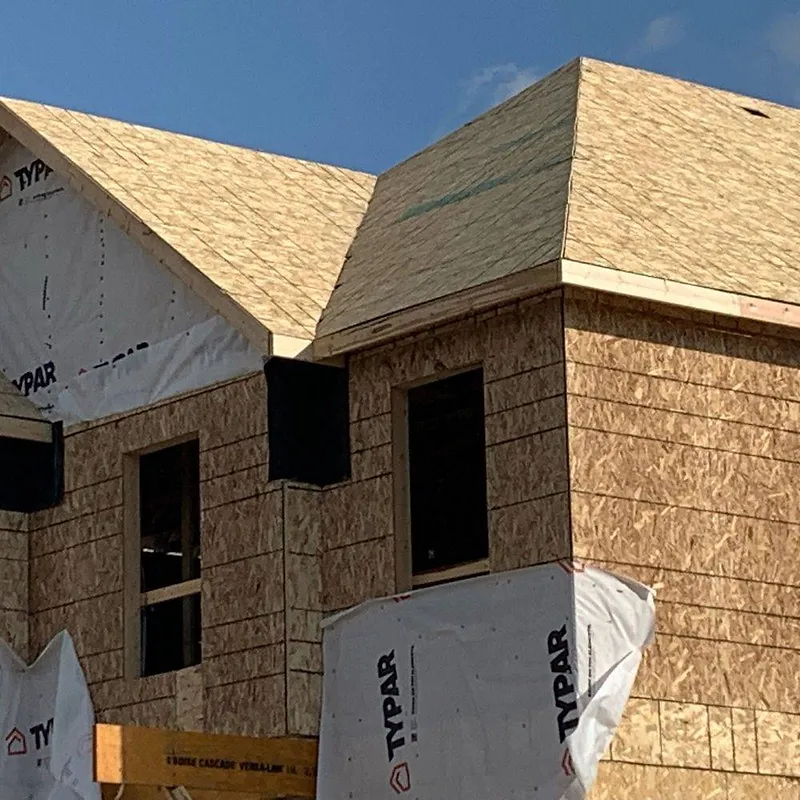 Construction of a house with exposed wood framing and sheathing, covered in Typar.