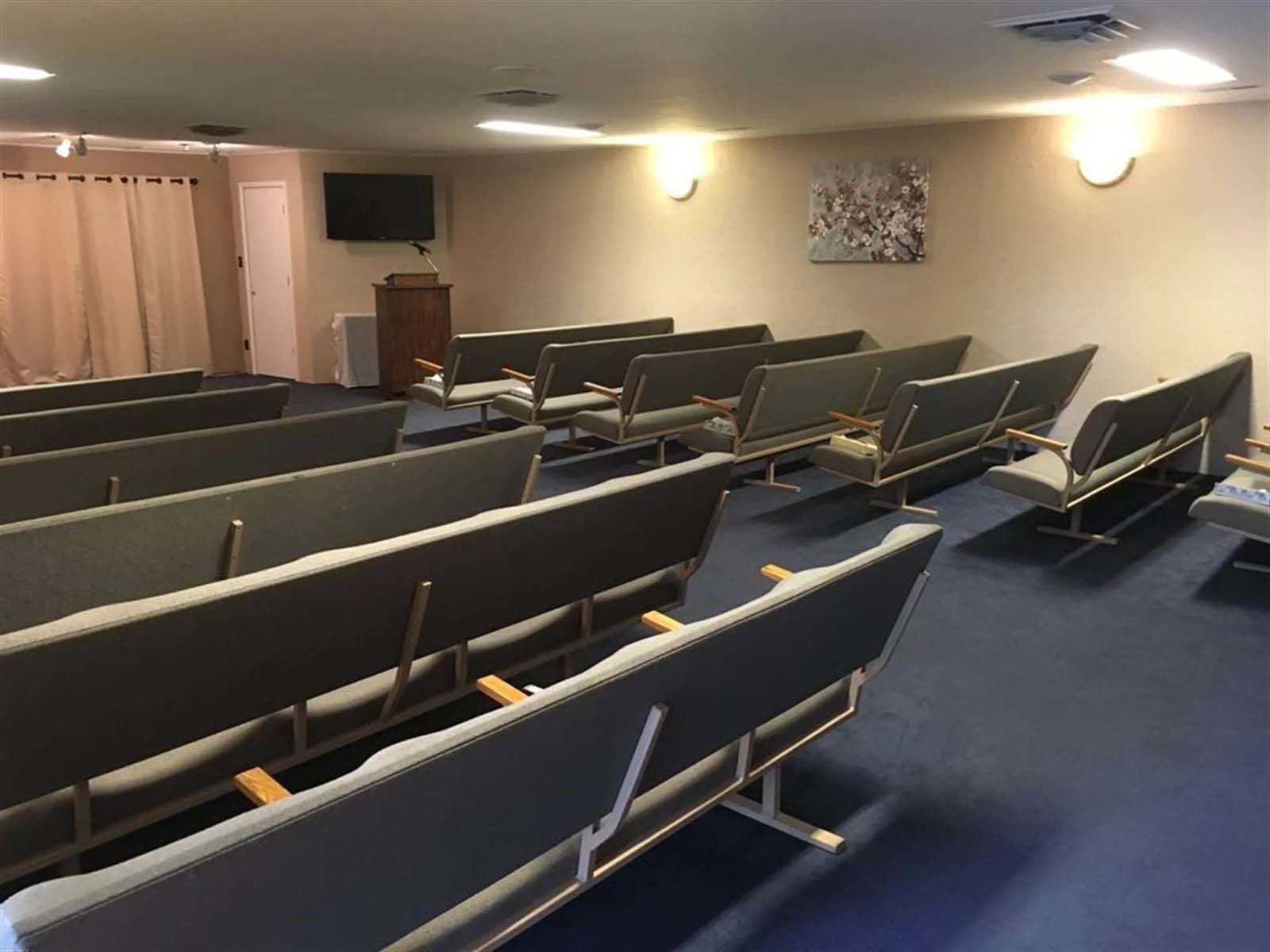 A room with rows of chairs and a television on the wall.