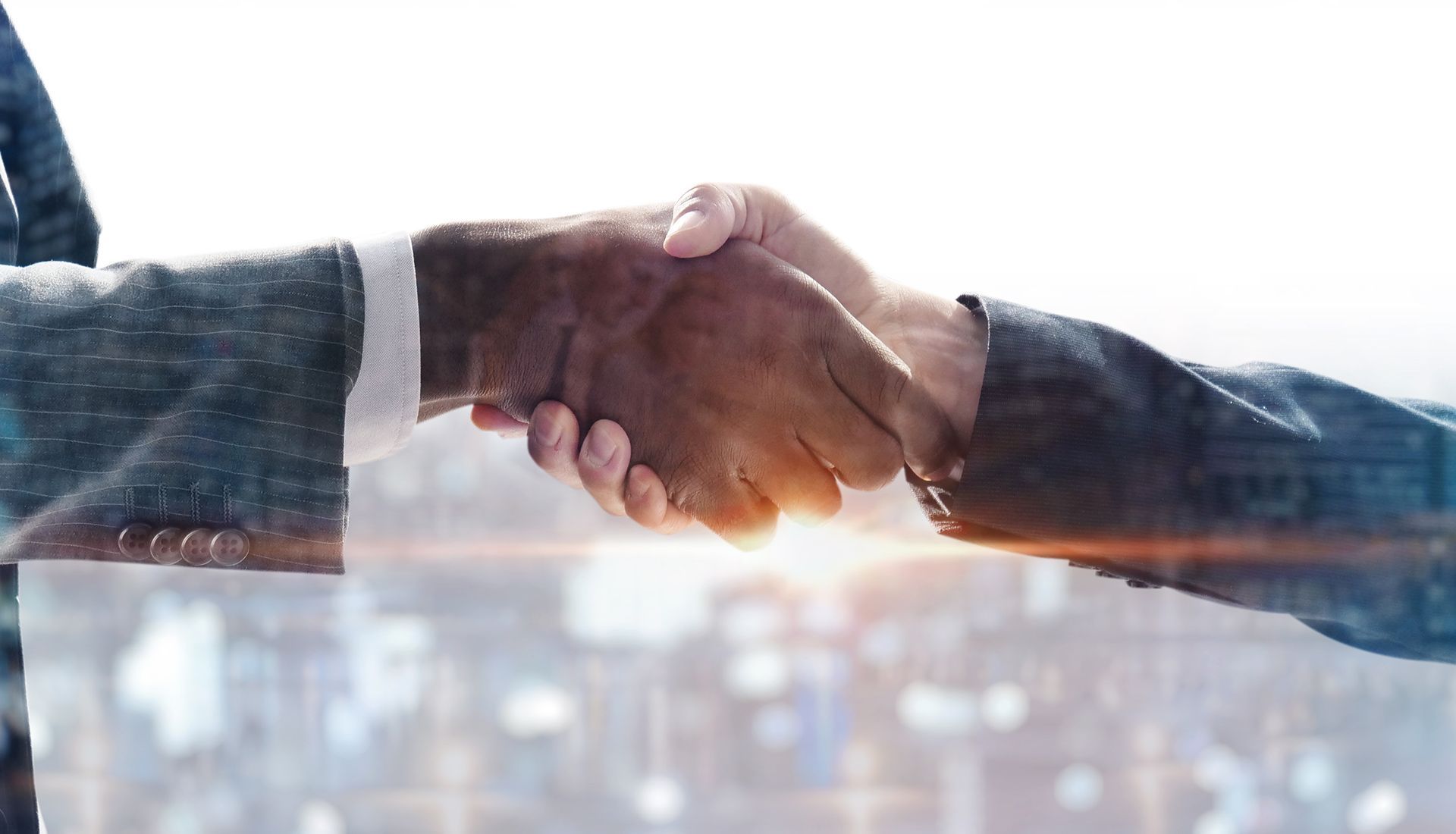 Two people in suits shaking hands, city backdrop.