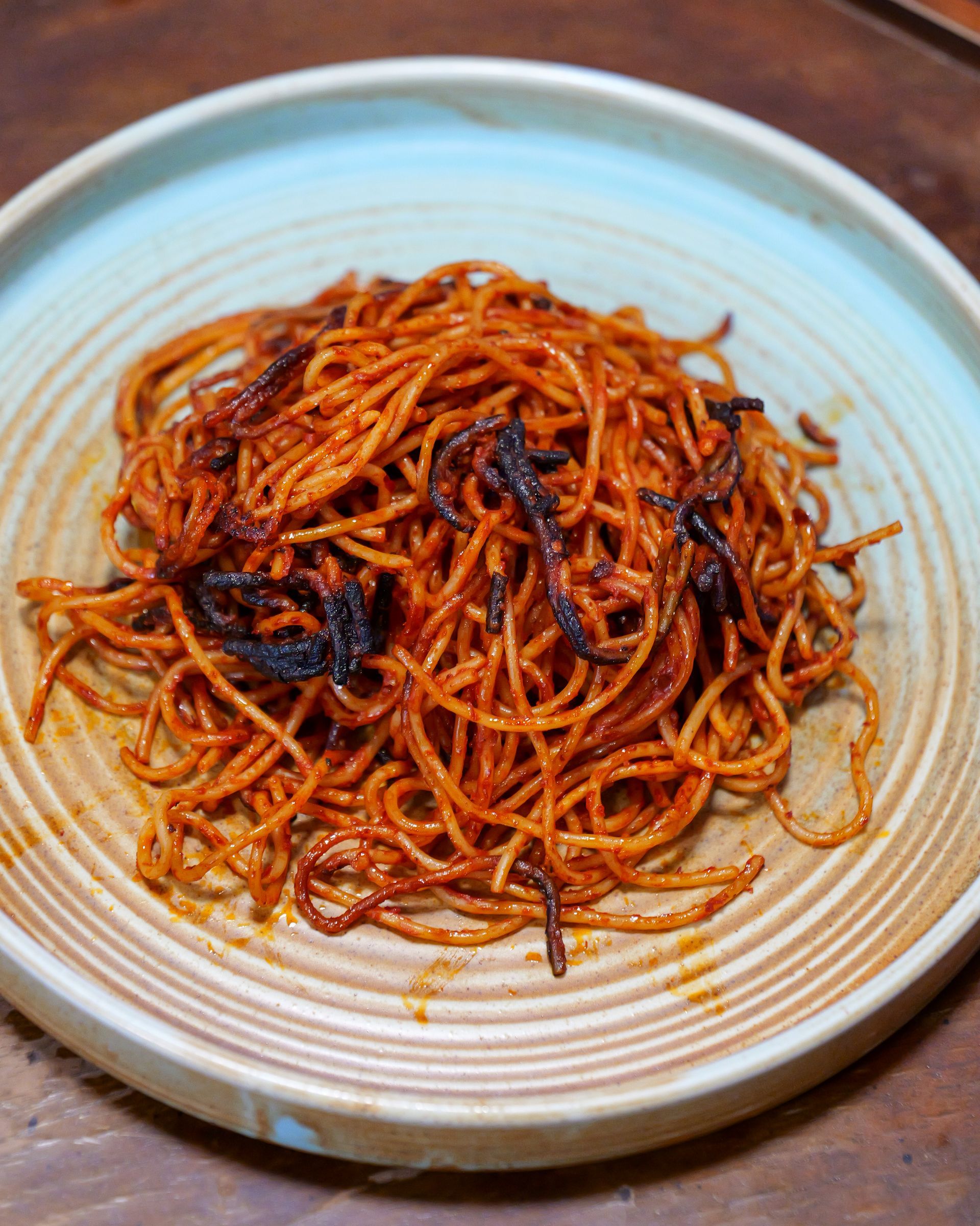 Piatto di carciofi con fette d'arancia e petali di fiori su un piatto bianco.