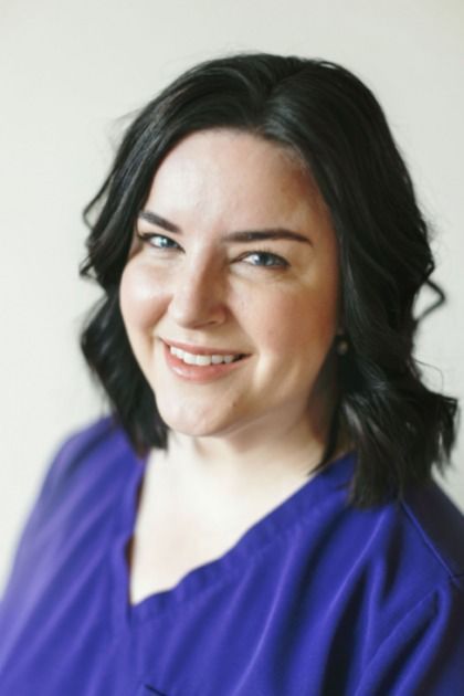 A woman in a purple shirt is smiling for the camera