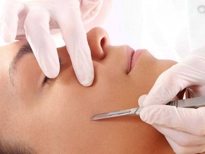 A woman is getting a facial treatment with a scalpel.