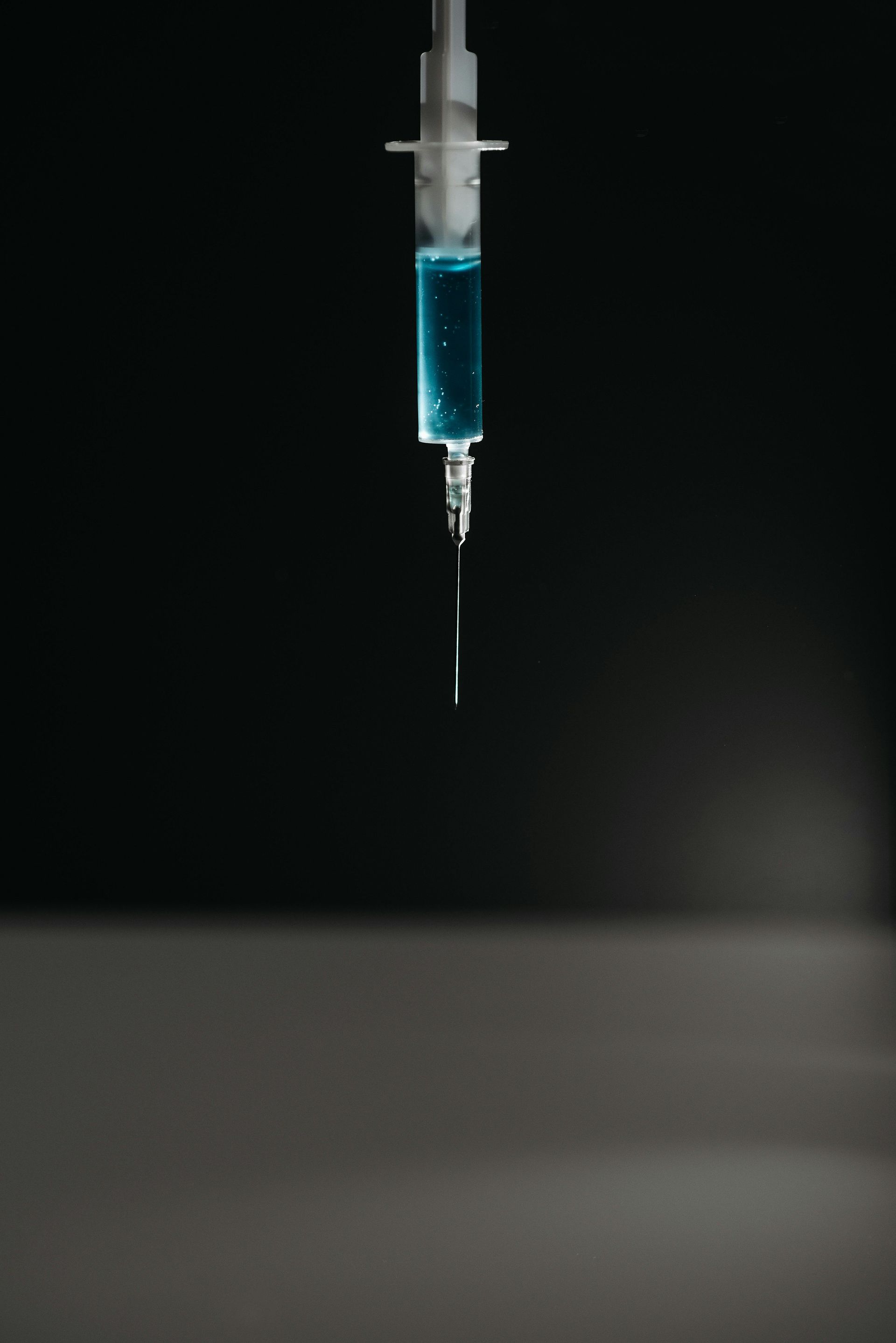 A close up of a syringe with a blue liquid in it.