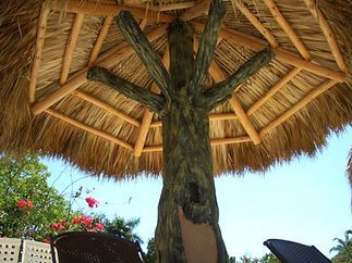 A thatched umbrella with a tree in the middle of it