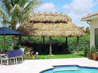 A house with a thatched roof and a swimming pool