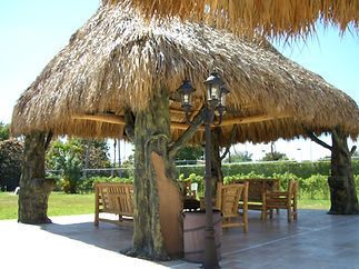 A thatched gazebo with a tree in the middle