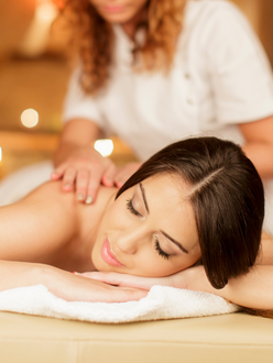 Woman receiving shoulder massage, eyes closed, spa setting.