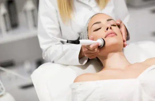 Woman receiving facial treatment in a spa, with a device on her face.