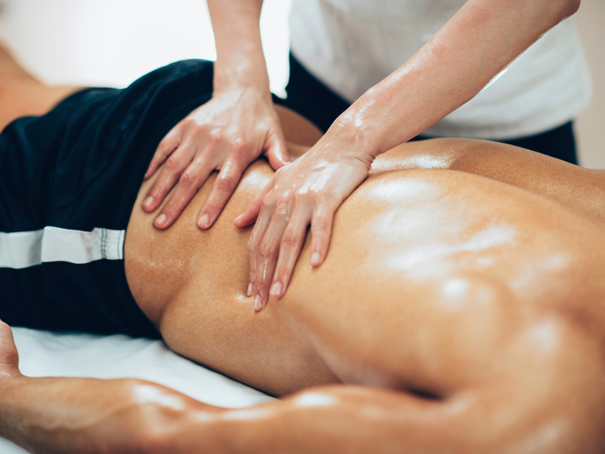 Person receiving a back massage on a white surface, with hands applying pressure.