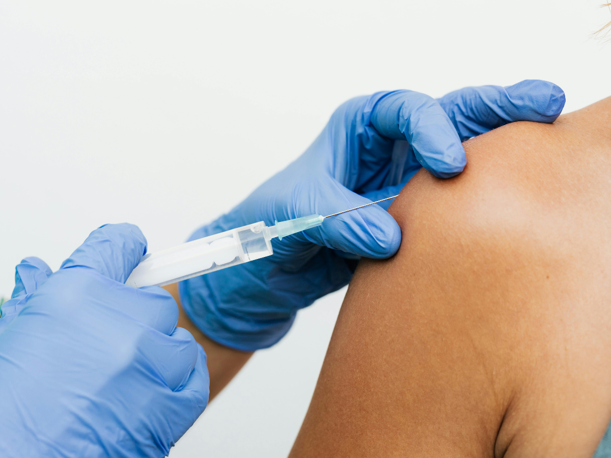 A gloved hand giving a shot in the arm.