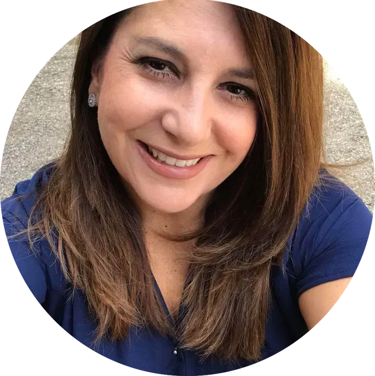 Woman with brown hair smiles at the camera; wearing a blue top.