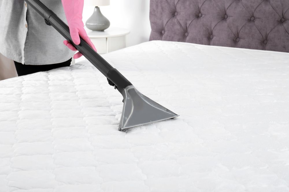Person Vacuuming a White Mattress with A Handheld Vacuum Cleaner — Clean Coast Carpet Cleaning in Port Stephens, NSW