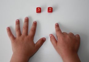 Kinderhandjes wijzen naar dobbelstenen