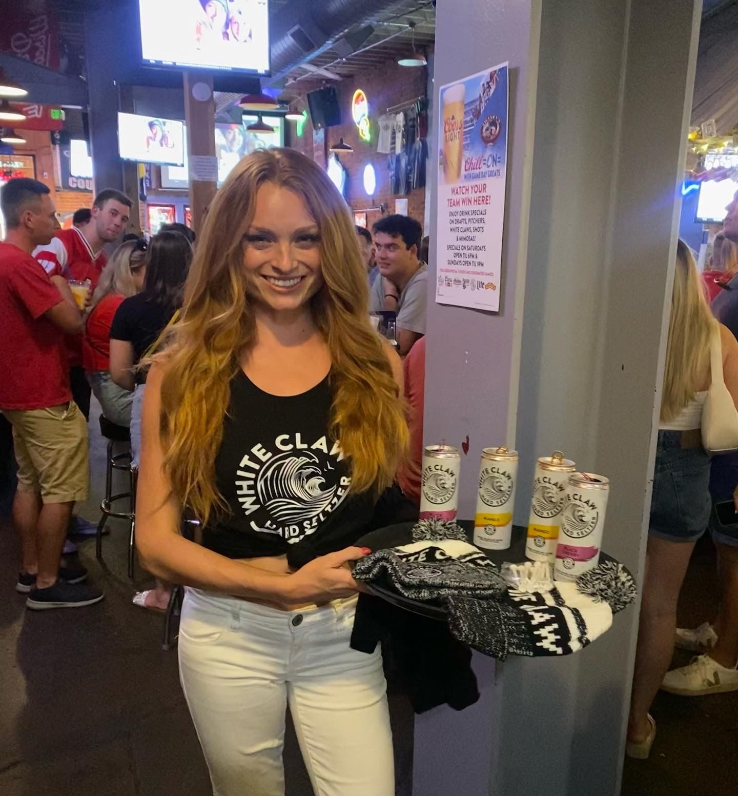 A woman wearing a black tank top that says white claw