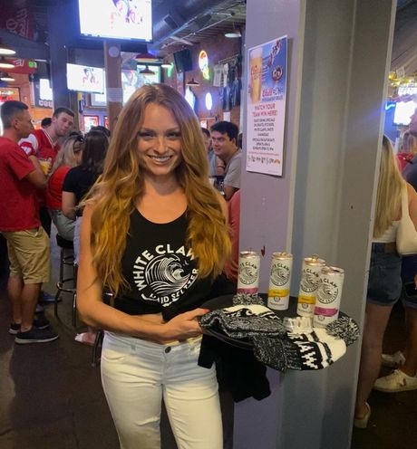 A woman wearing a black tank top that says white claw