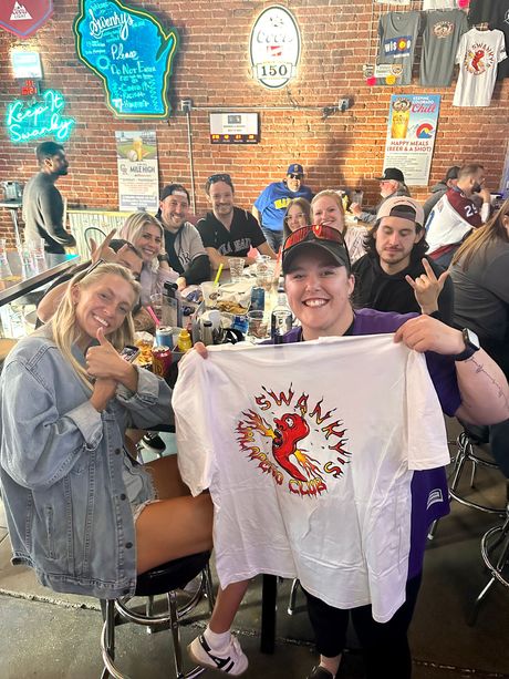 A group of people are sitting at a table in swankys, denver's #1 midwest sports bar 