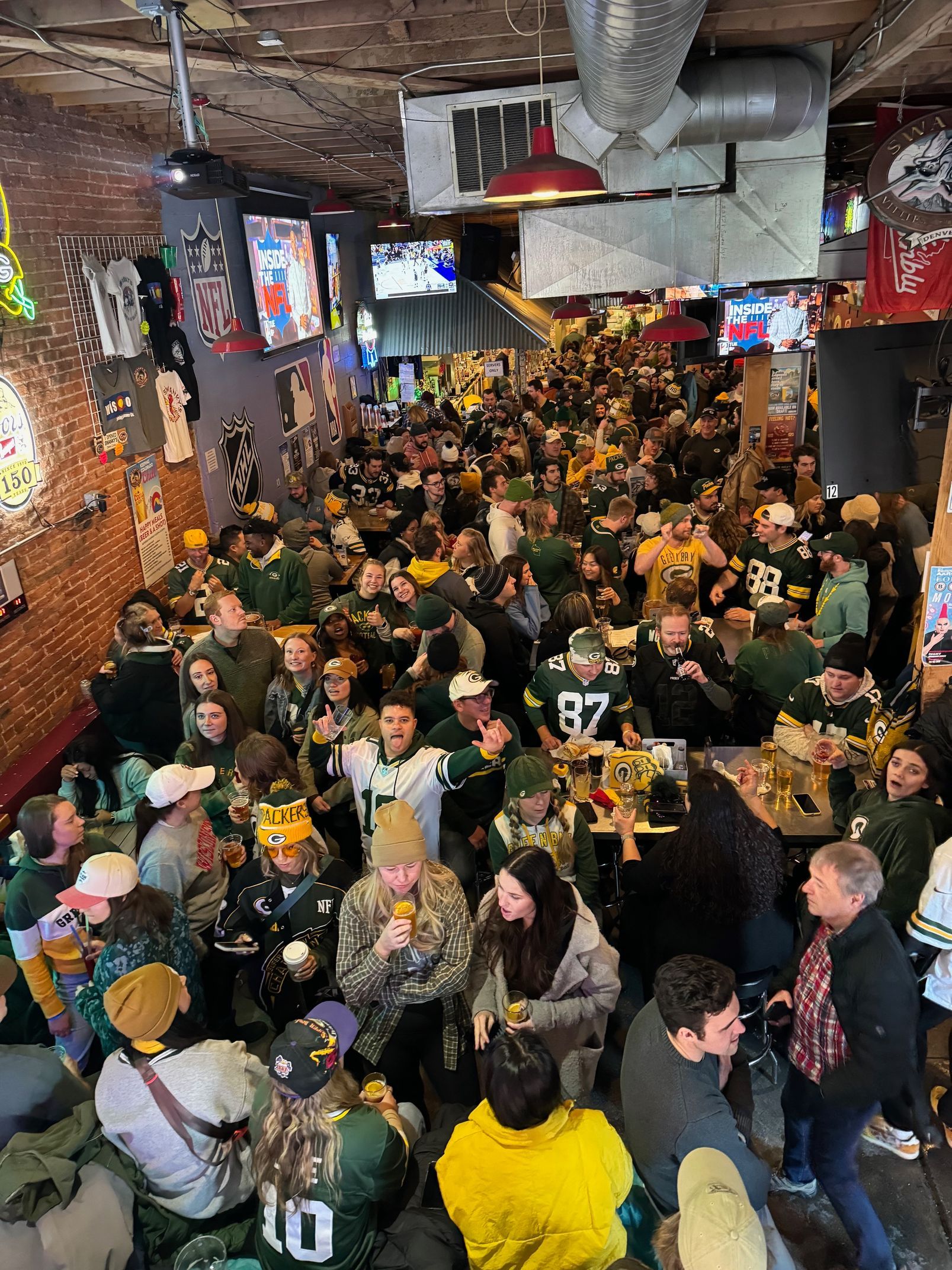 A crowd of people are watching a football game in swankys, denver's #1 midwest sports bar