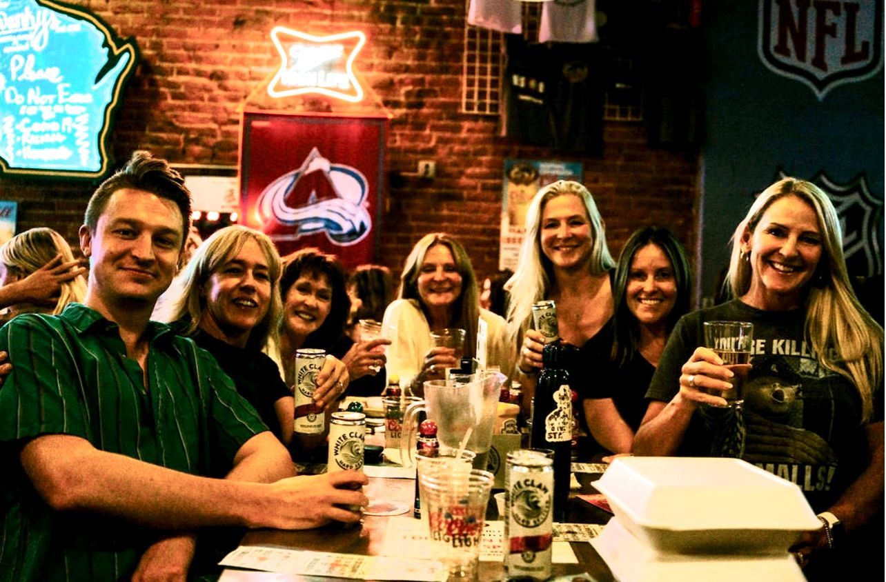 A group of people are sitting at a table drinking beer at swankys midwest sports bar in denver, colorado