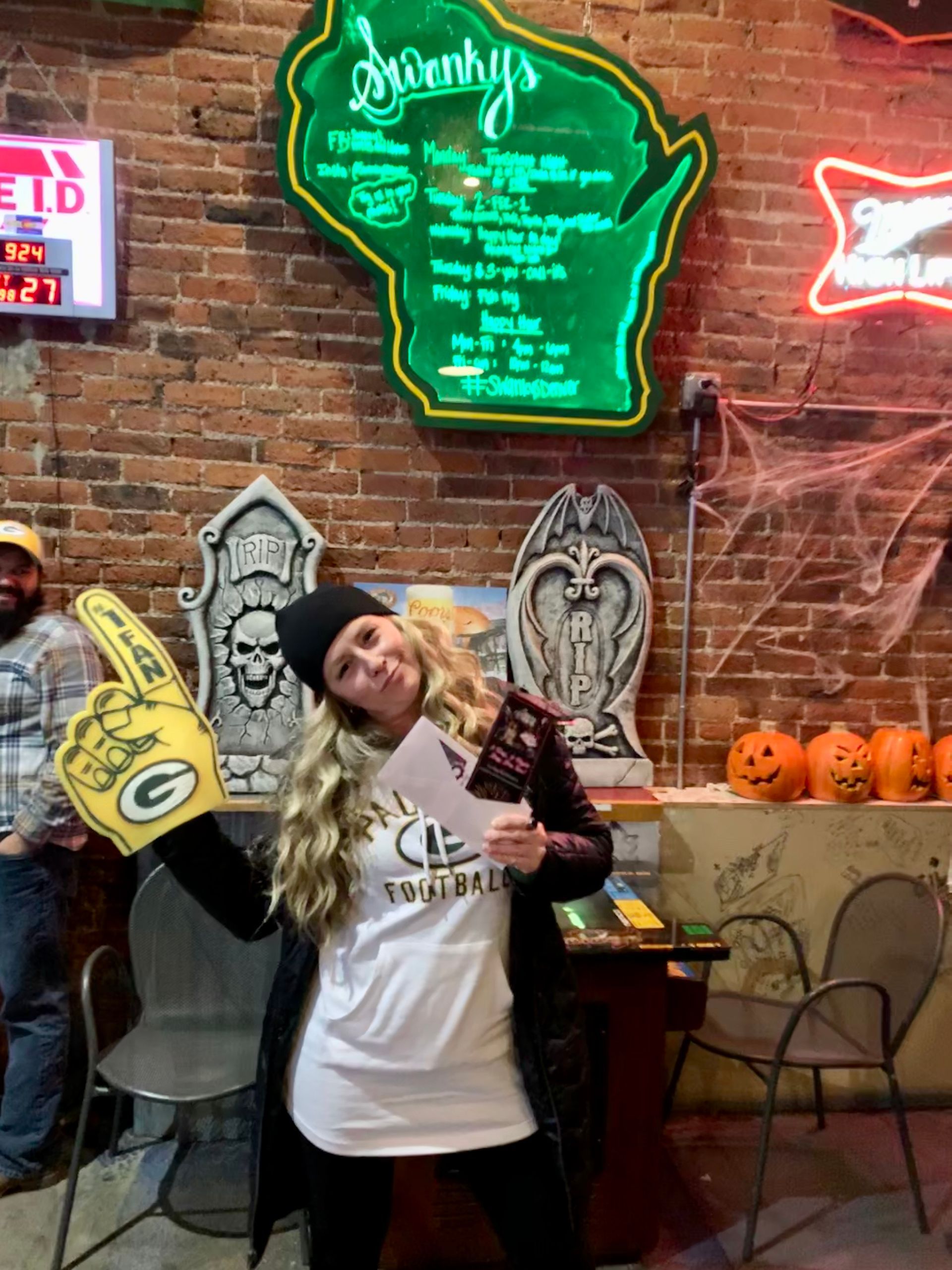 A woman in a green bay packers costume is holding a green bay packers finger.